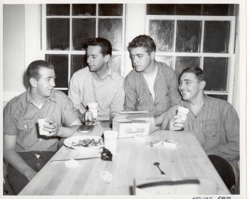The original caption stated: "Rescuers discuss the rescue. Left to right are Coast Guardsmen Bernard Webber, who piloted the rescue boat; Engineman second class Andrew Fitzgerald, Seaman Richard Livesey and Seaman Irving Maske. Photo by Richard Kelsey, Chatham." Photo credit: Cape Cod Community College.